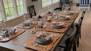 A long dining table set with placemats, plates, glasses, and cutlery, surrounded by chairs. - Private Beach - 3 bedroom (Orleans)