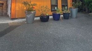 A building with a wooden facade, a glass balcony, and potted plants in front. - Rustic modern garden level suite (North Vancouver)