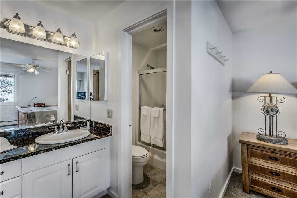 A bathroom with a sink, mirror, vanity, and a shower area.