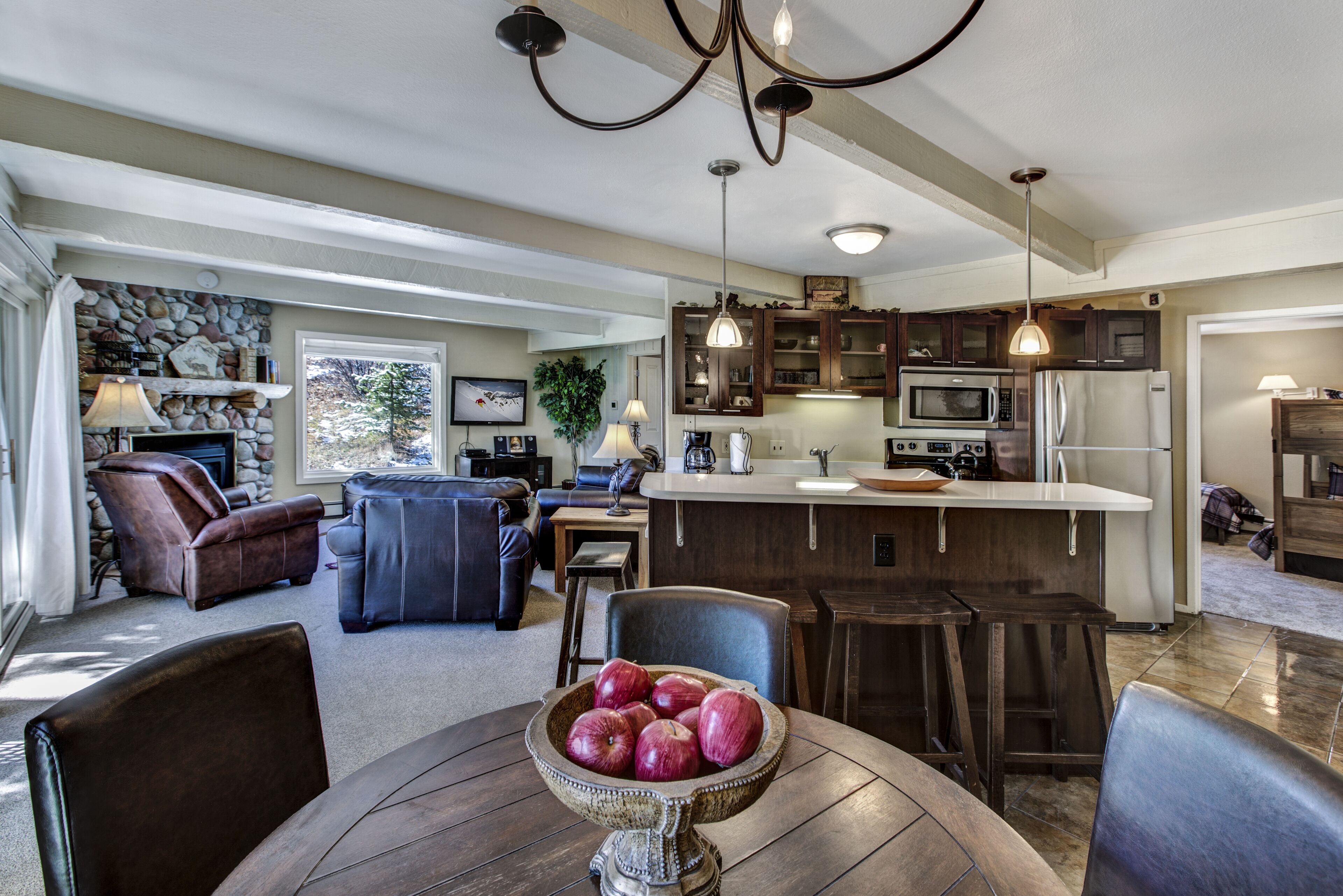 A modern kitchen with a central island, dark wooden cabinets, and a dining area with a round table and chairs.