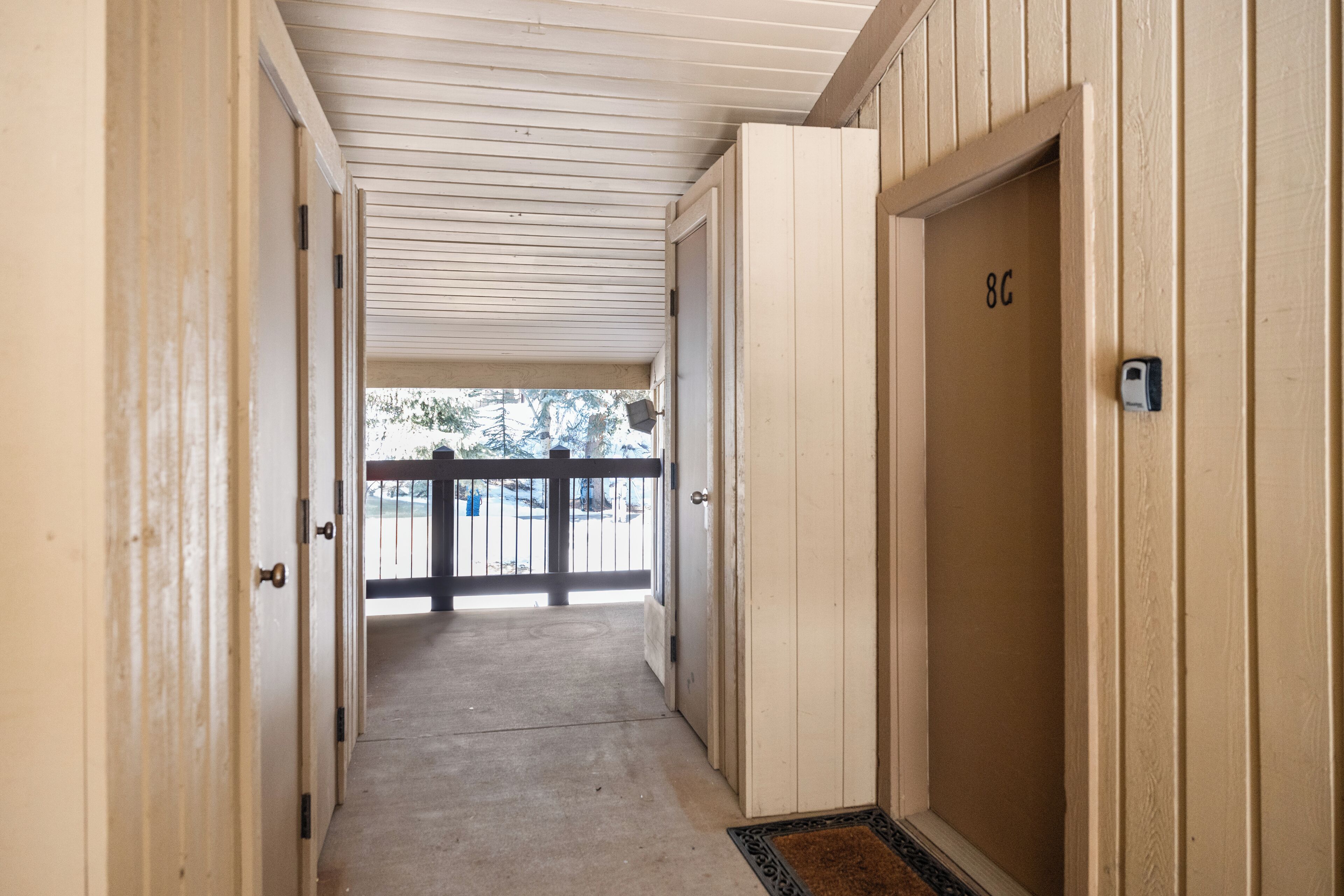 A corridor with doors, a balcony, and a view of the outside.