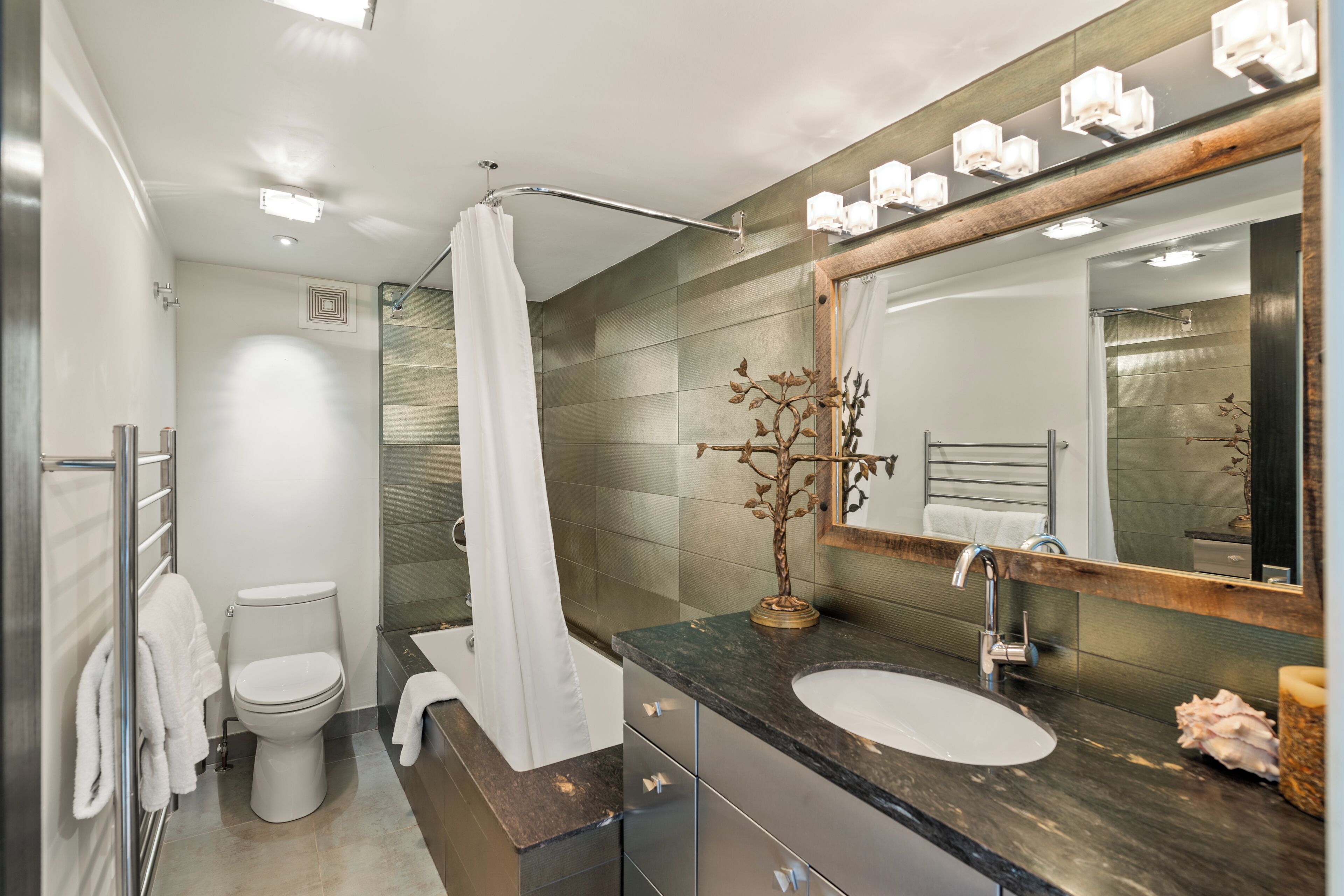 Un baño moderno con ducha, inodoro, lavabo y un espejo grande.