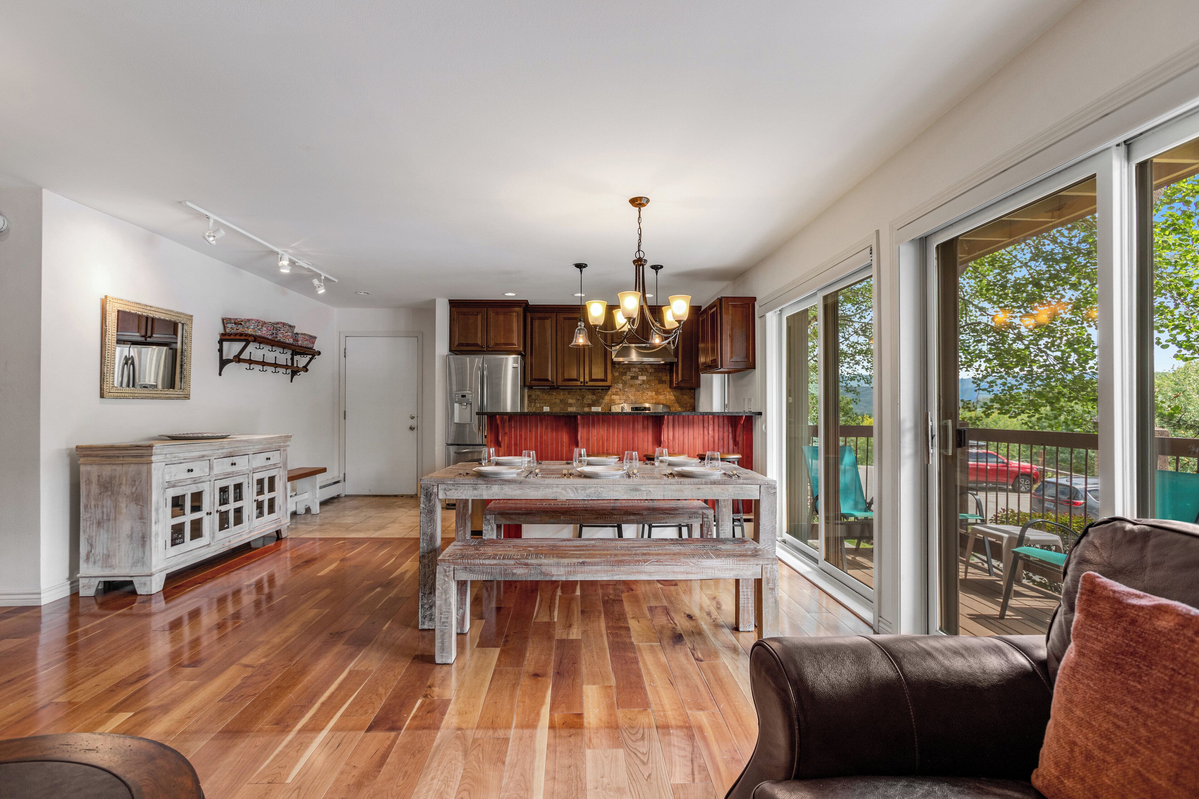 A spacious kitchen with wooden cabinets, a stainless steel refrigerator, and a large dining table with benches.