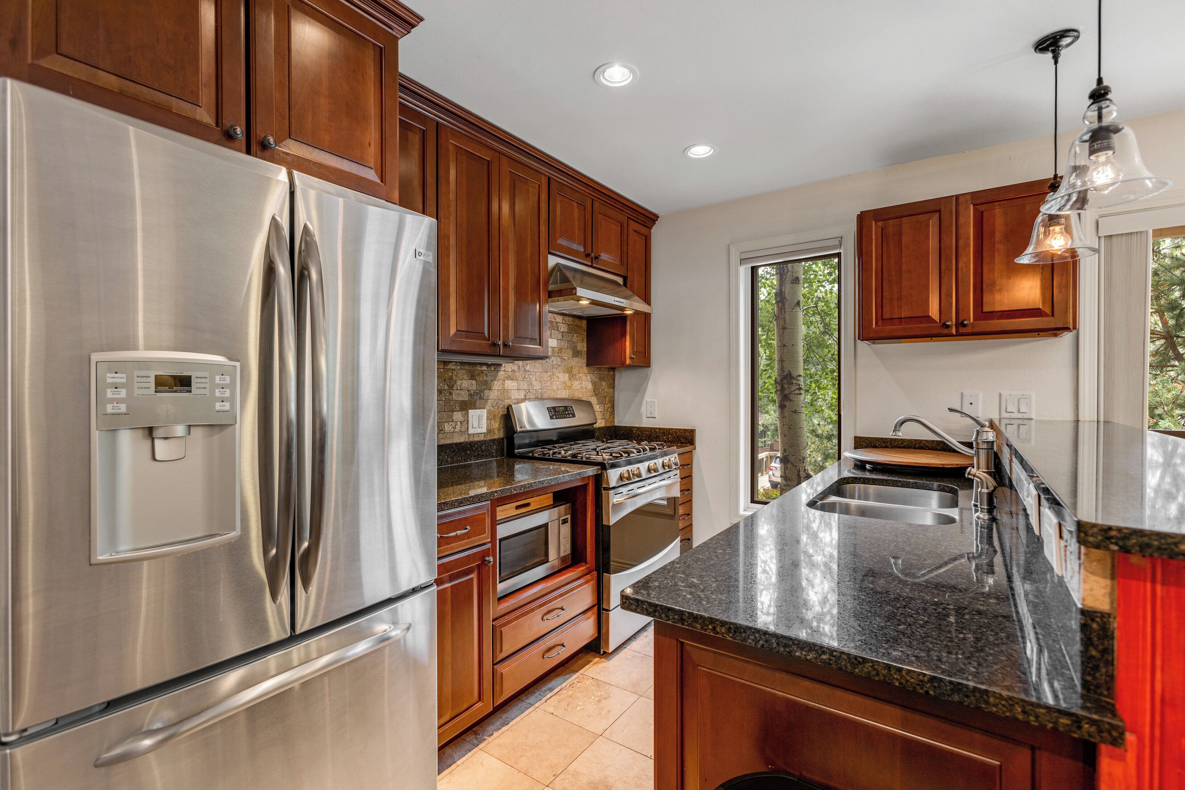 A modern kitchen with stainless steel appliances, wooden cabinets, and a granite countertop.