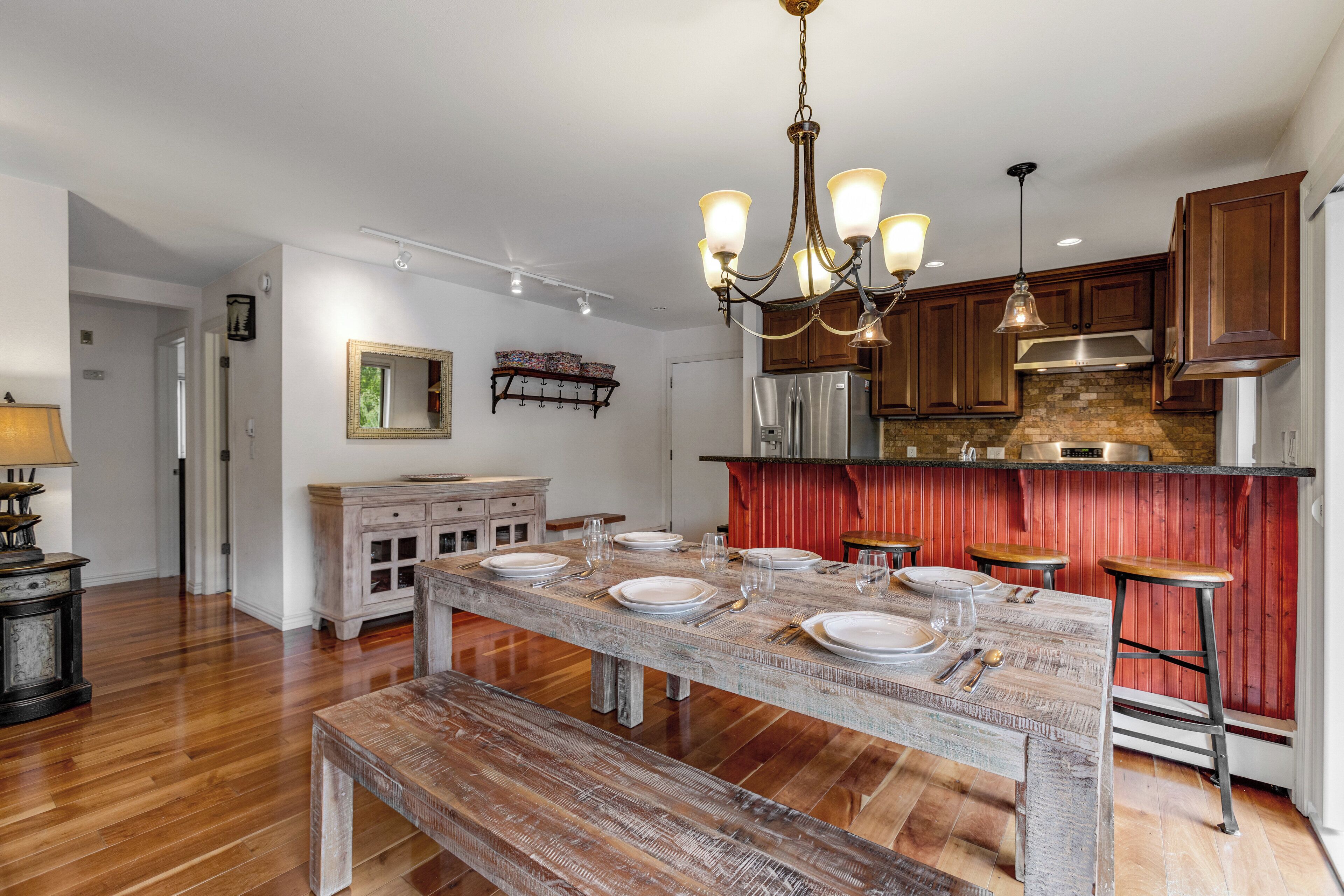 Una cocina amplia con piso de madera, una gran mesa de comedor preparada para seis comensales y electrodomésticos modernos.