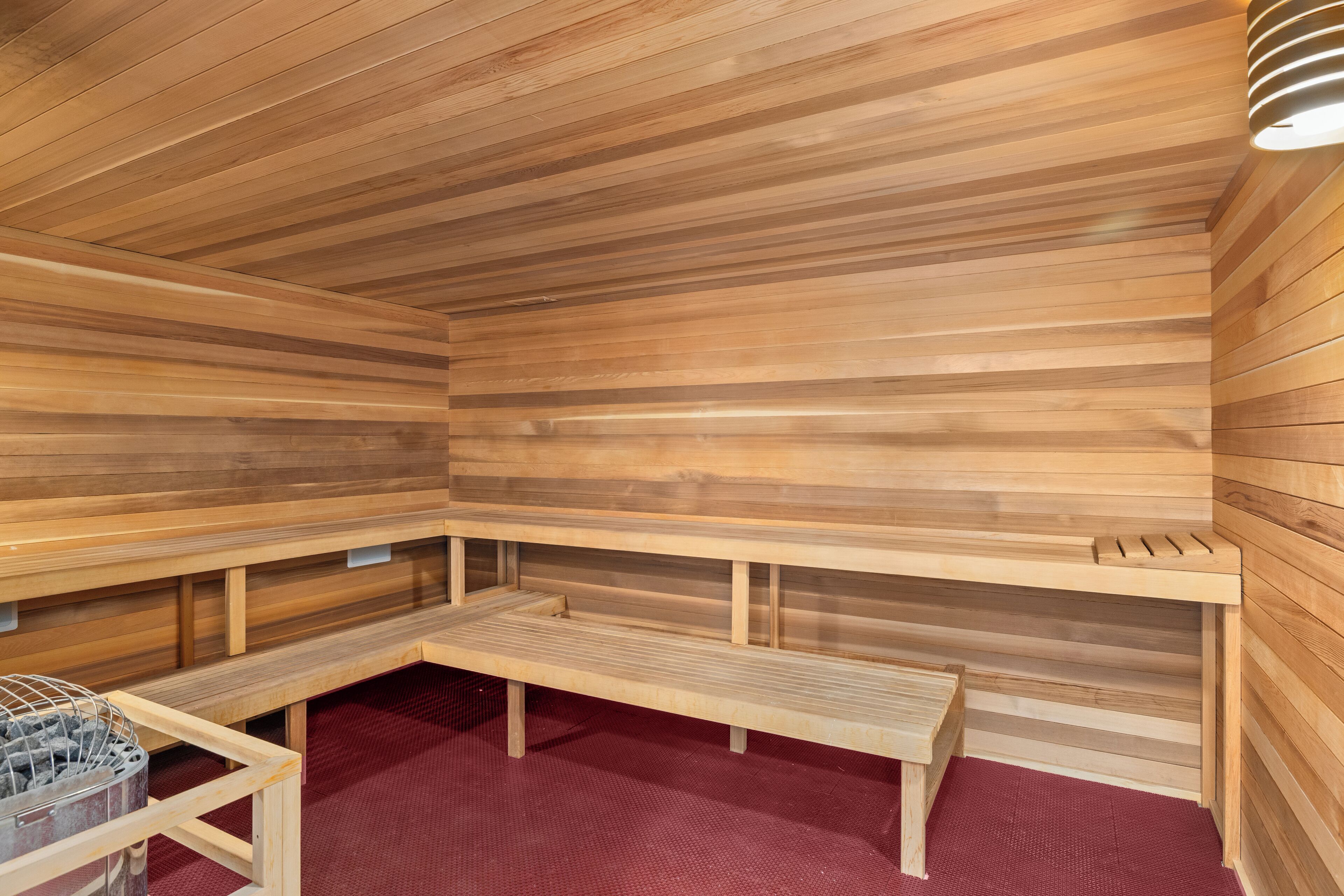 Una sauna con bancos de madera y suelo cubierto de alfombra roja.