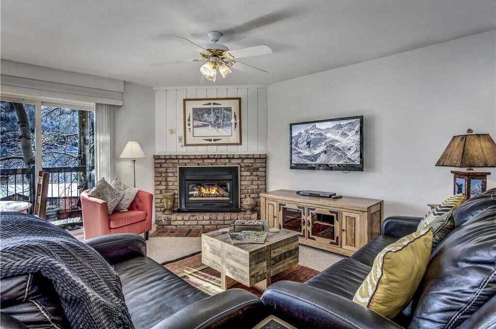 A cozy living room with a fireplace, leather sofas, and a television.