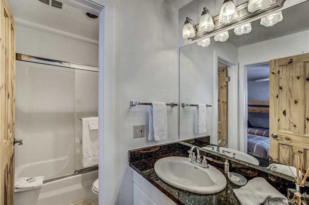 A bathroom with a bathtub, a sink, and a large mirror.