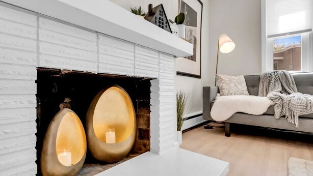 A modern living room with a white fireplace, a grey sofa, and a floor lamp. - Benelo | Midcentury Modern Single-Level Home, 3 BR (Sioux Falls)