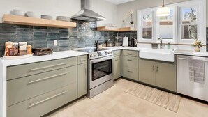 A modern kitchen with a built-in oven, stainless steel appliances, and a large window providing natural light. - Benelo | Midcentury Modern Single-Level Home, 3 BR (Sioux Falls)