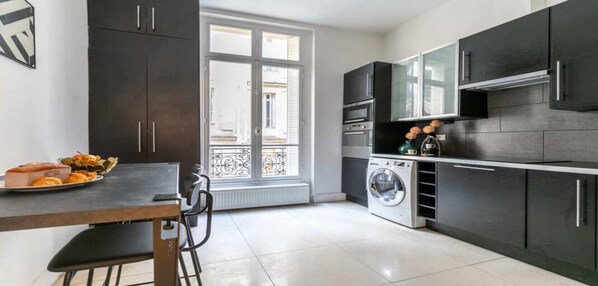 Enjoy meals in this kitchen with a dining table and chairs, a washing machine, and a convenient countertop.
