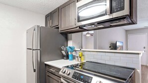 A modern kitchen with stainless steel appliances, including a refrigerator, oven, and microwave. - SoCo 2BR corner suite, king bed, fast WiFi w/ pool (Austin)