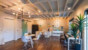 A modern kitchen with wooden cabinets, a dining area with a round table and chairs, and a large window with a view of the outdoors. - SoCo 2BR corner suite, king bed, fast WiFi w/ pool (Austin)