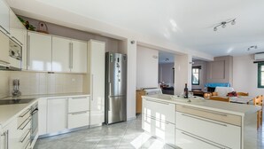Eine moderne Küche mit weißen Schränken, einem Edelstahlkühlschrank und einem Essbereich mit Tisch und Stühlen.
