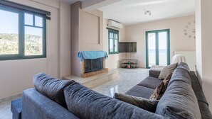 Ein modernes Wohnzimmer mit Kamin, einem großen grauen Sofa und einem Flachbildfernseher.