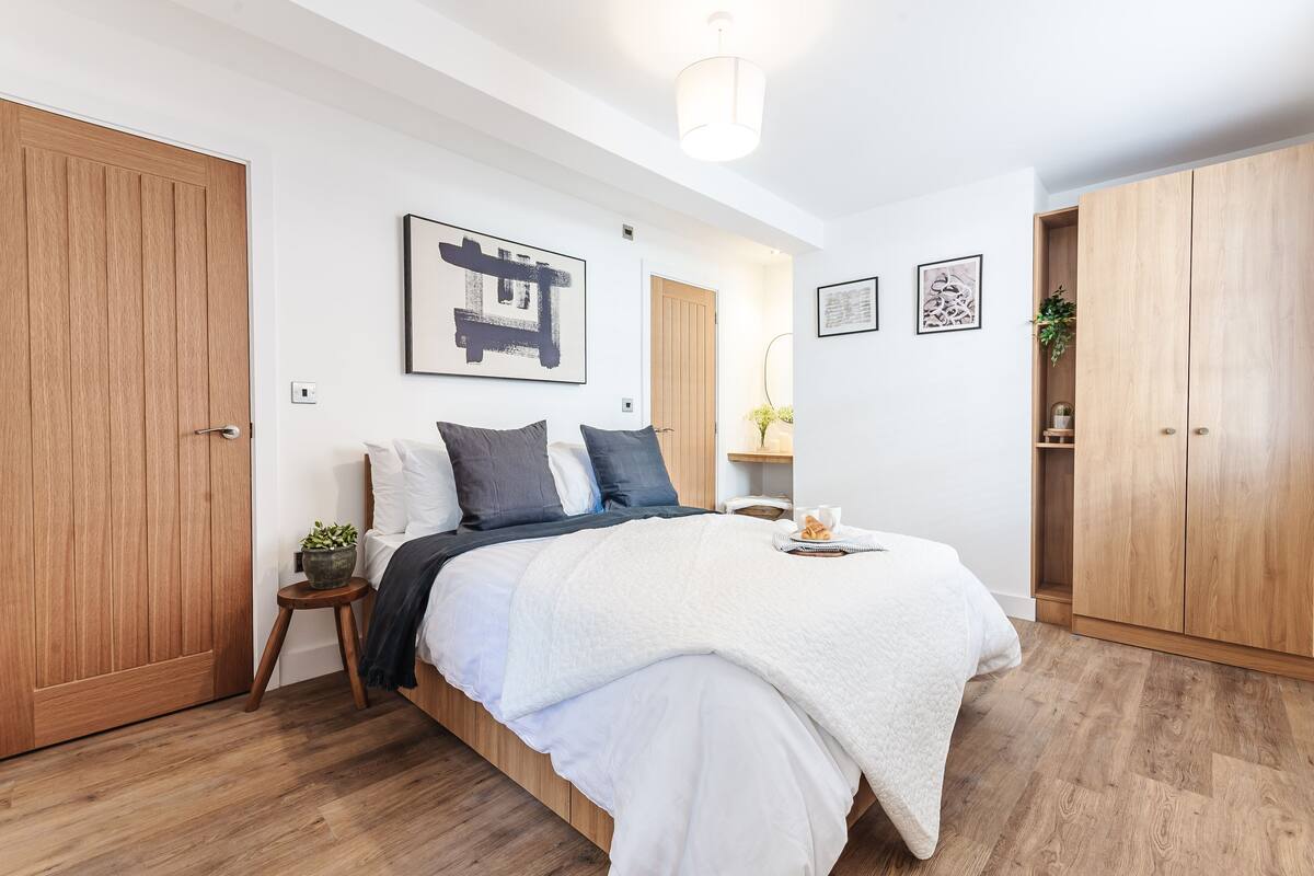 Een slaapkamer met een houten bed, een nachtkastje met een plant en een grote kledingkast.