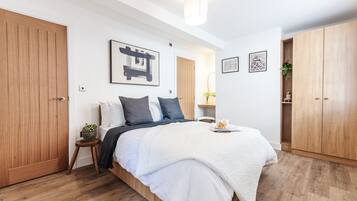 A bedroom with a wooden bed, a bedside table with a plant, and a large wardrobe.