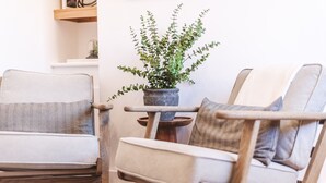 Een moderne woonkamer met een houten fauteuil, een klein houten tafeltje en een plant in pot.