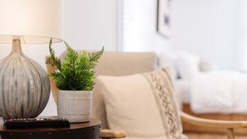 A living room with a lamp, a potted plant, a remote control, and a sofa.