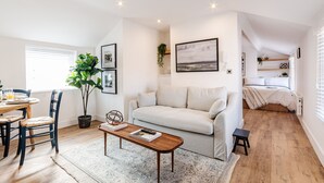 Een ruime woonkamer met een bank, een eettafel met stoelen, een salontafel en een potplant.