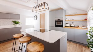 Een moderne keuken met een centraal eiland, barstoelen, een inbouwoven en een houten aanrecht.