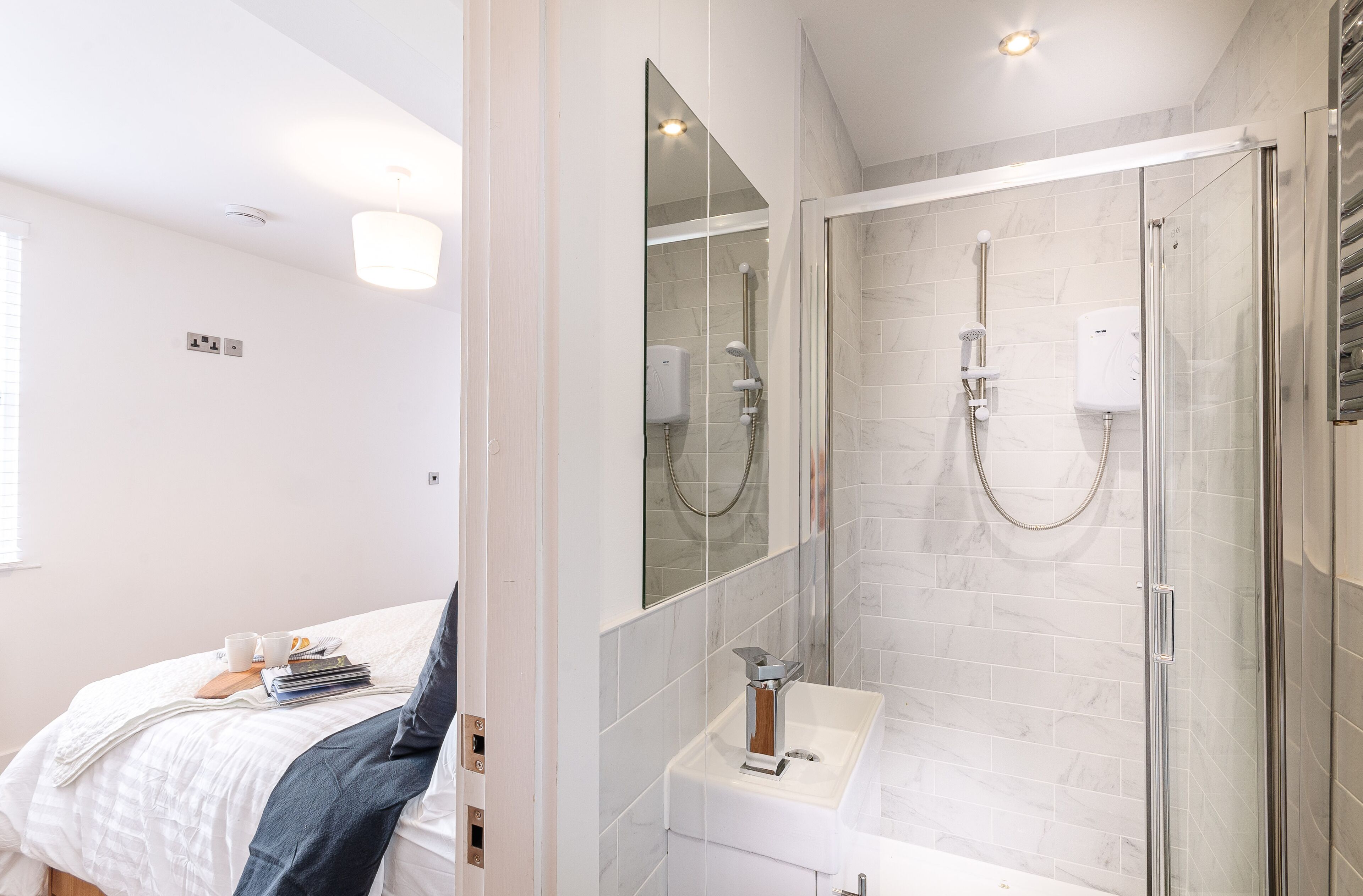 A modern bathroom with a glass-enclosed shower, a white sink, and a large mirror.
