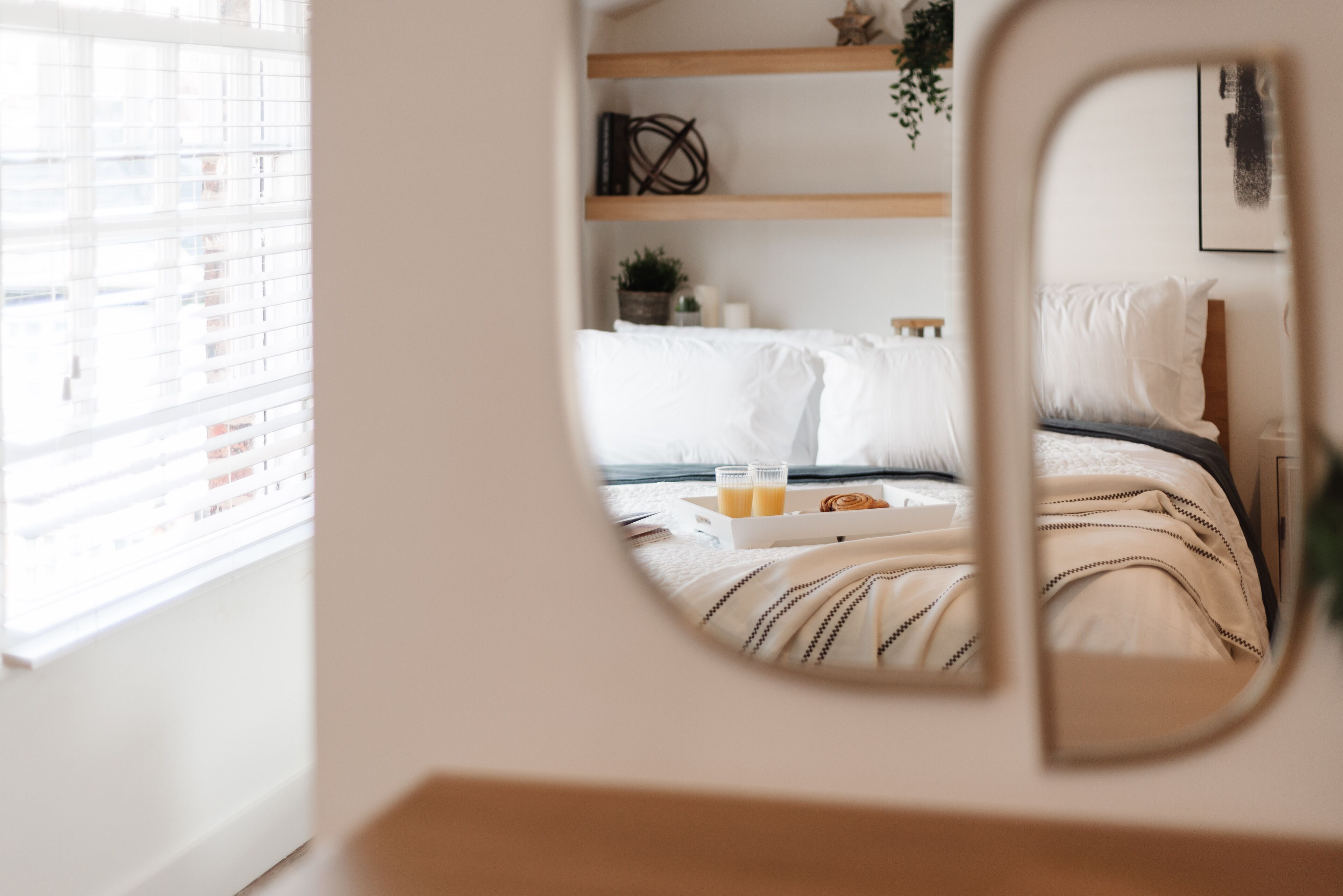 A bedroom with a bed, bedside table, and a window with blinds.