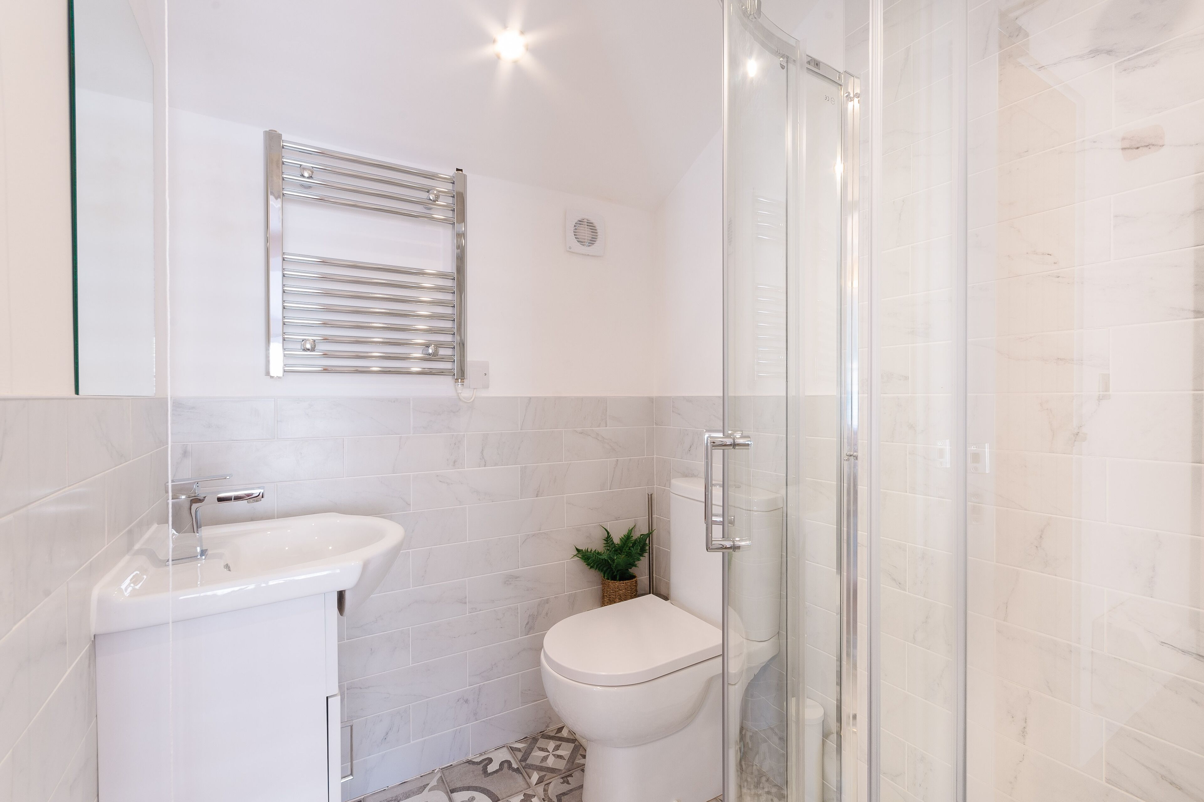 A modern bathroom with a glass shower enclosure, a white sink, and a toilet.