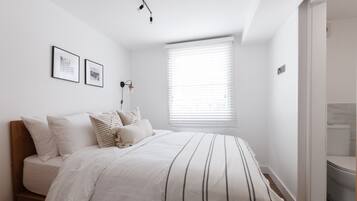 Una camera da letto con un letto, una finestra con persiane e un punto luce fissato al muro.