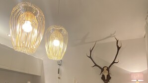Ein Essbereich mit Holztisch und Stühlen, einer Kronleuchter, einem Wandaufsatz aus Hirschgeweihen und einem kleinen Tisch mit Pflanze.
