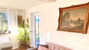 Ein Wohnzimmer mit einem beigen Sofa, einem braunen Lederteppich und einem Fenster mit weißen Vorhängen.