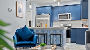 A modern kitchen with blue cabinets, stainless steel appliances, and a central island. - Newly- updated home, a block away from the beach! (Miramar Beach)