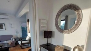 Un salon moderne avec un canapé, une table basse, un téléviseur et une cheminée. Il y a un miroir au mur et une fenêtre avec des rideaux.