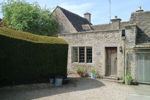 A stone building with a window and a door, surrounded by gravel and potted plants.