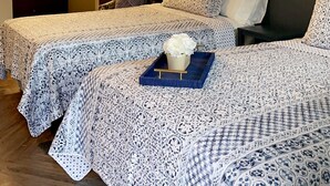 Una habitación de hotel con dos camas, una mesita de noche, un espejo y decoración en la pared.