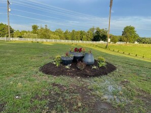 A landscaped area with a white fence, a grassy field, and a row of potted plants. - Hotel Lake Anna (Spotsylvania)