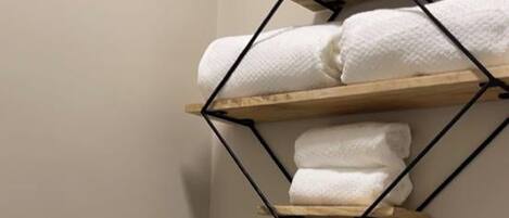 Un baño con inodoro, rollo de papel higiénico y toallero con toallas.