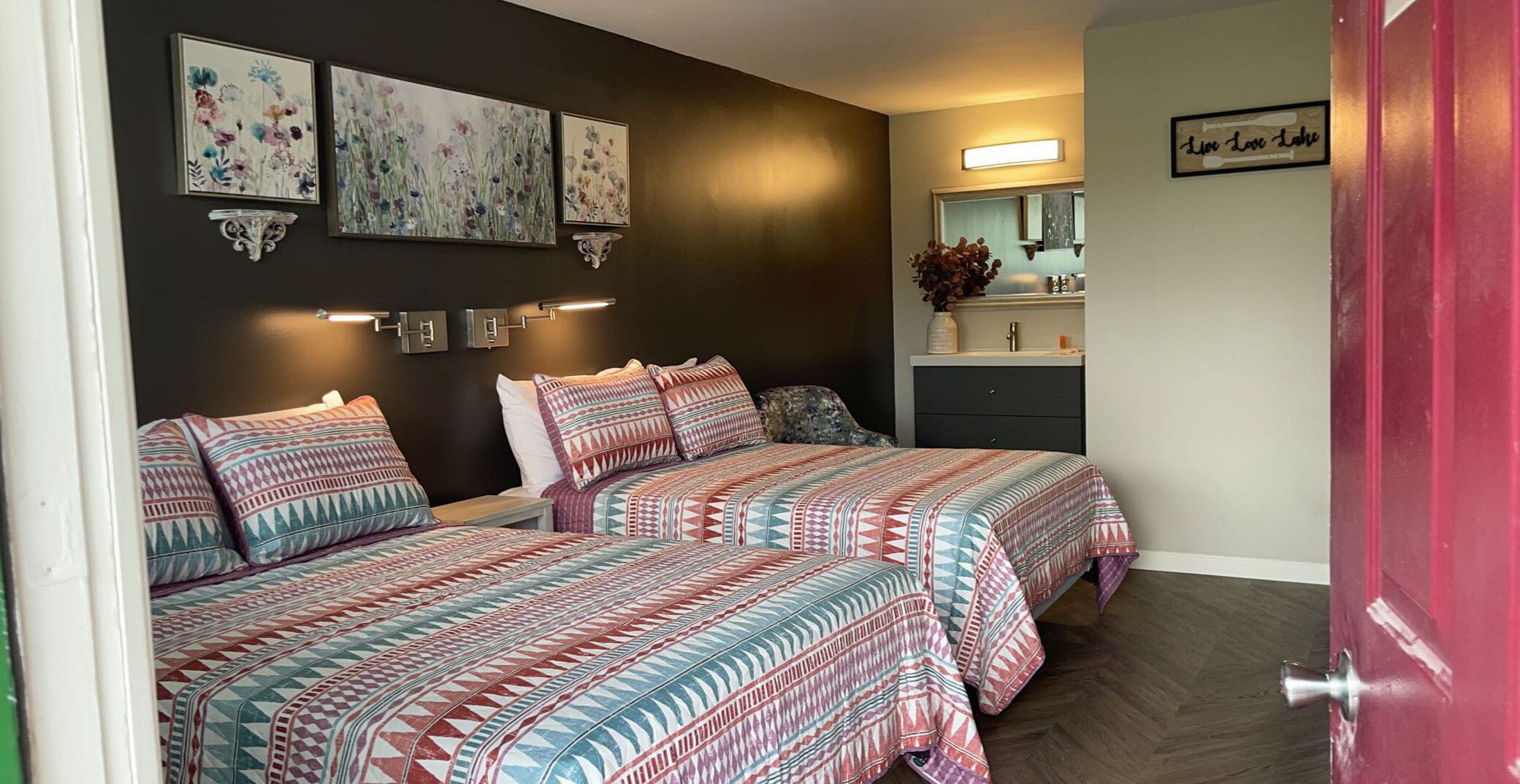 A bedroom with two beds, a dresser, a mirror, and wall art.