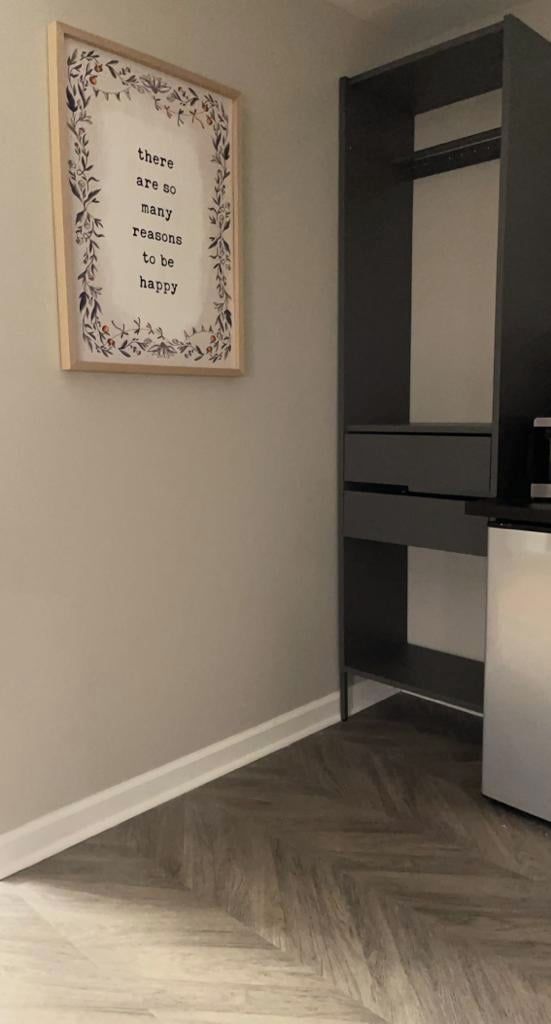 A room with a framed quote on the wall, a built-in bench, and a herringbone-patterned floor.