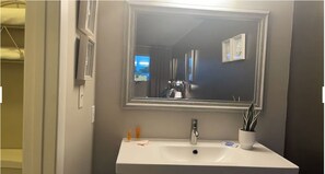 A bathroom with a white sink, a mirror, and a window. - Hotel Lake Anna (Spotsylvania)