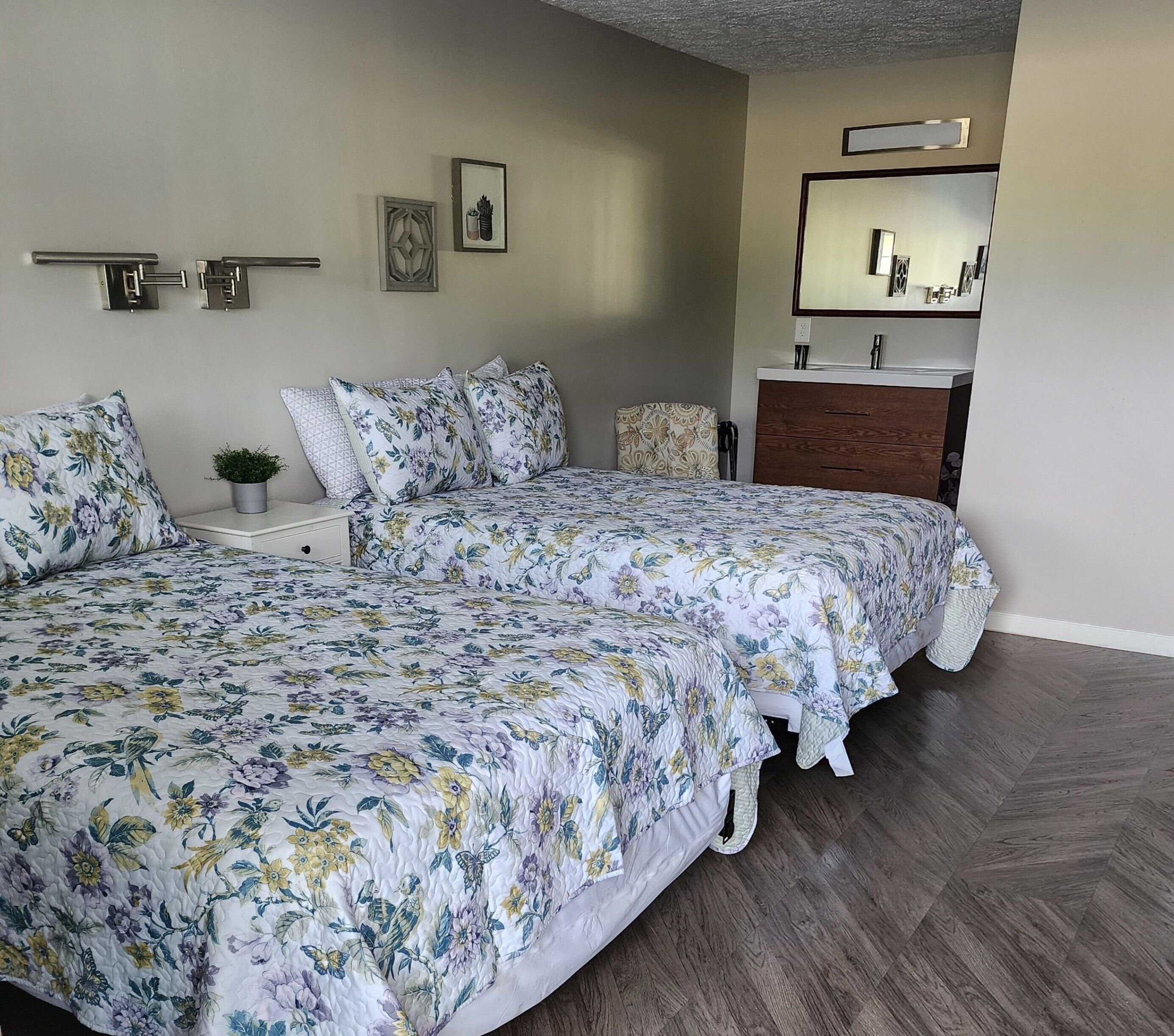 Een slaapkamer met een groot bed, een nachtkastje met een plant, een kast en een spiegel boven de kast.