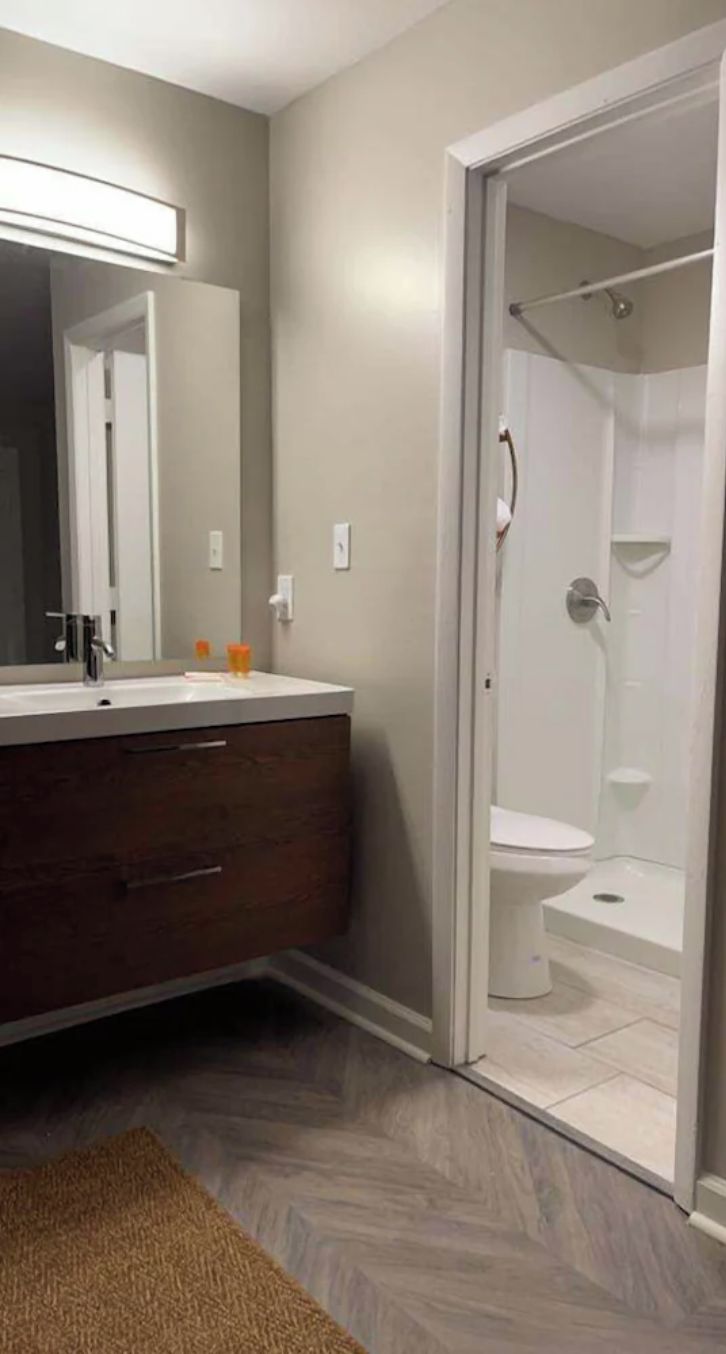 A bathroom with a vanity, mirror, and shower.