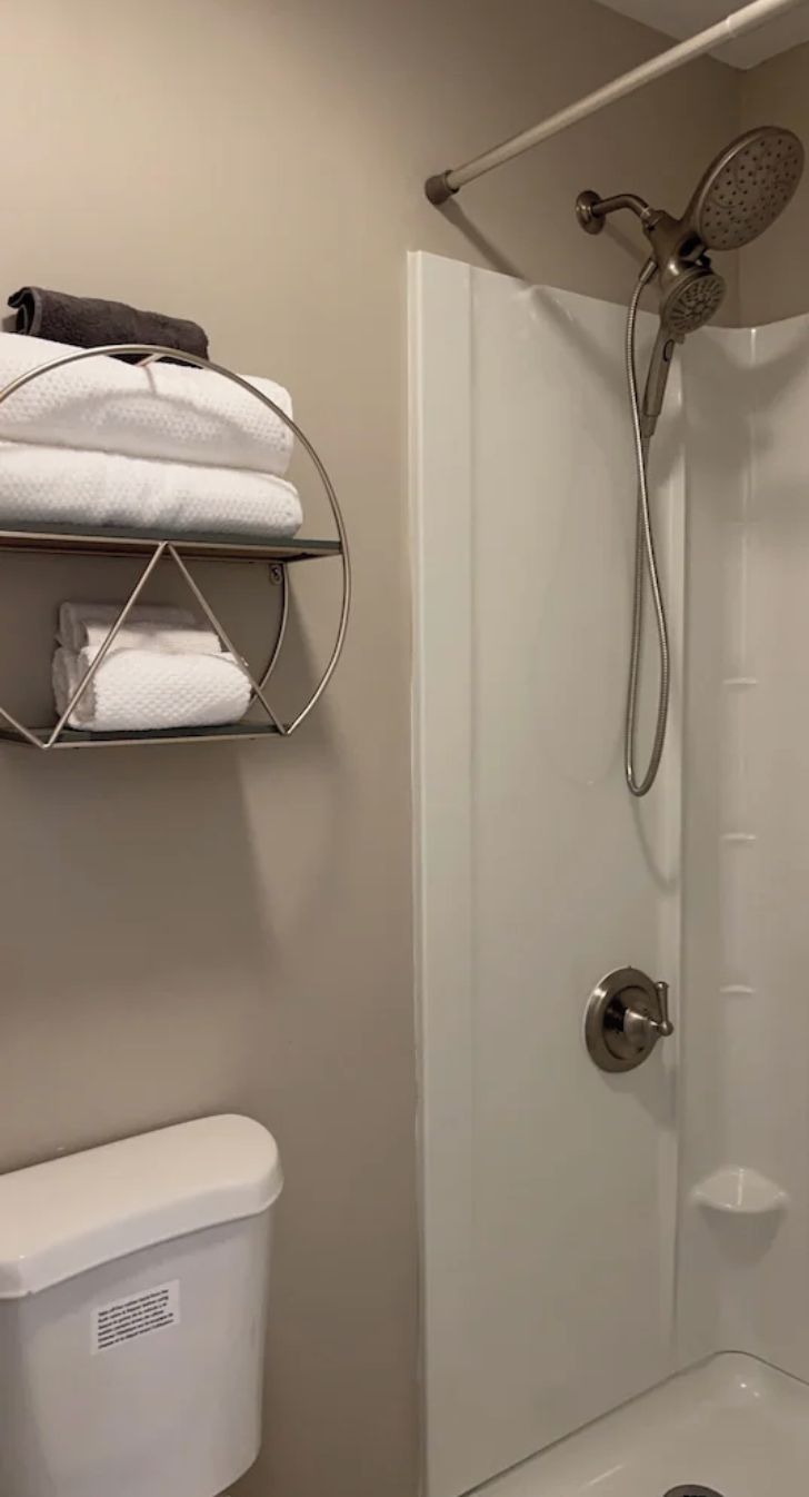 Un baño con ducha, inodoro y toallero con toallas dobladas.