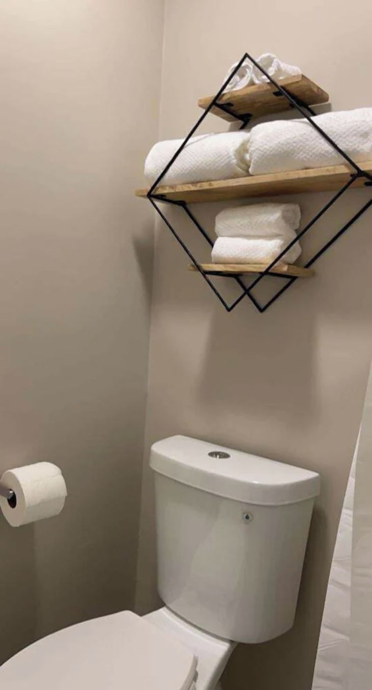 A bathroom with a toilet, a roll of toilet paper, and a towel rack with towels.