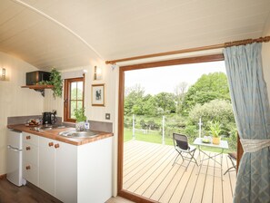 Una cocina con encimera de madera, un lavamanos y armarios. Hay una ventana con vista a un jardín y una terraza afuera.