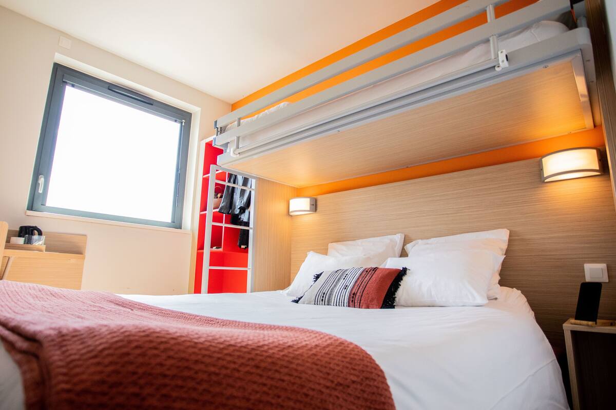 A hotel room with a bed, a window, a wardrobe, and a nightstand.