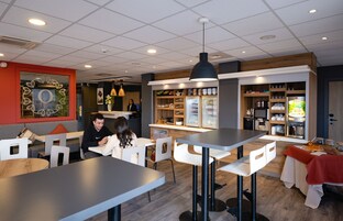Una cafetería moderna con asientos, una barra y una exhibición de alimentos.
