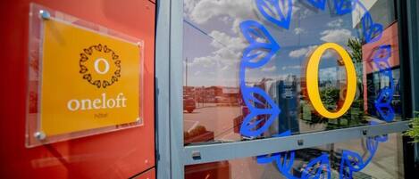 A hotel sign with the name 'oneloft' and a glass window with a blue leaf design.