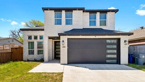 A modern two-story house with a garage, large windows, and a well-maintained lawn.