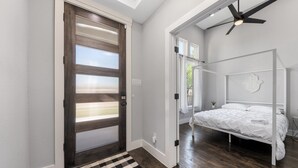 A bedroom with a bed, a ceiling fan, and a view through an open door.